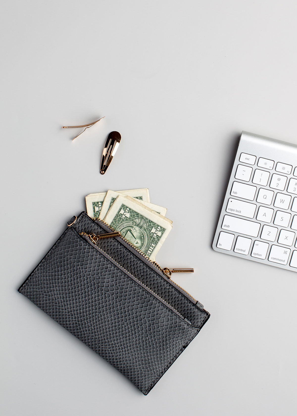 a wallet with dollar bills coming out of it next to a keyboard.