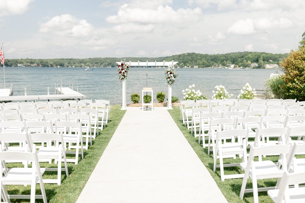 Ceremony at Bay Pointe Inn Pavilion during Mackenzie & Russell’s Shelbyville Michigan wedding with sunset over Gun Lake