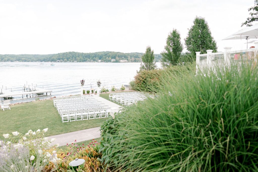 Ceremony at Bay Pointe Inn Pavilion during Mackenzie & Russell’s Shelbyville Michigan wedding with sunset over Gun Lake
