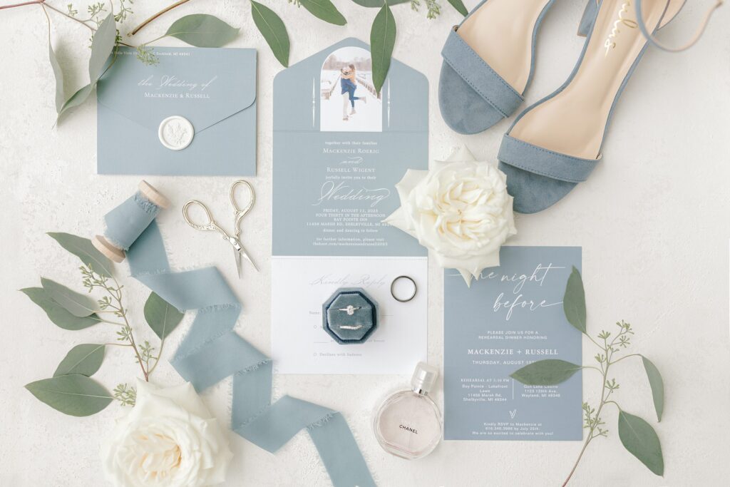 Wedding details including rings, flowers, and invitations at Mackenzie & Russell’s Shelbyville Michigan Bay Pointe Inn wedding