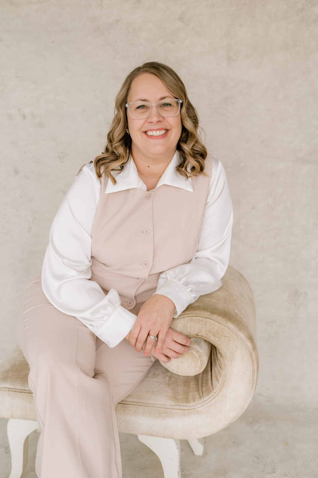 Kara Hanes, Grand Rapids wedding photographer, seated in a light and airy studio portrait
