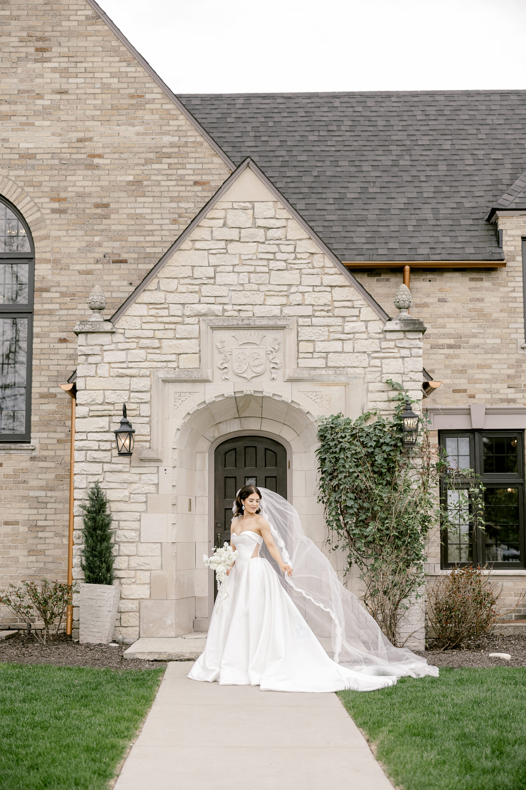 Bride with flowing veil standing in front of the historic Venue 3Two mansion in Grand Rapids Michigan photographed by Kara Hanes