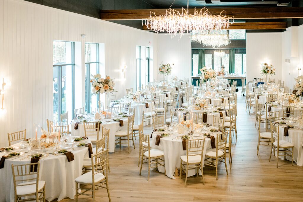 White Pine Hall reception space at Hidden Grove Estate set with gold chiavari chairs and crystal chandeliers