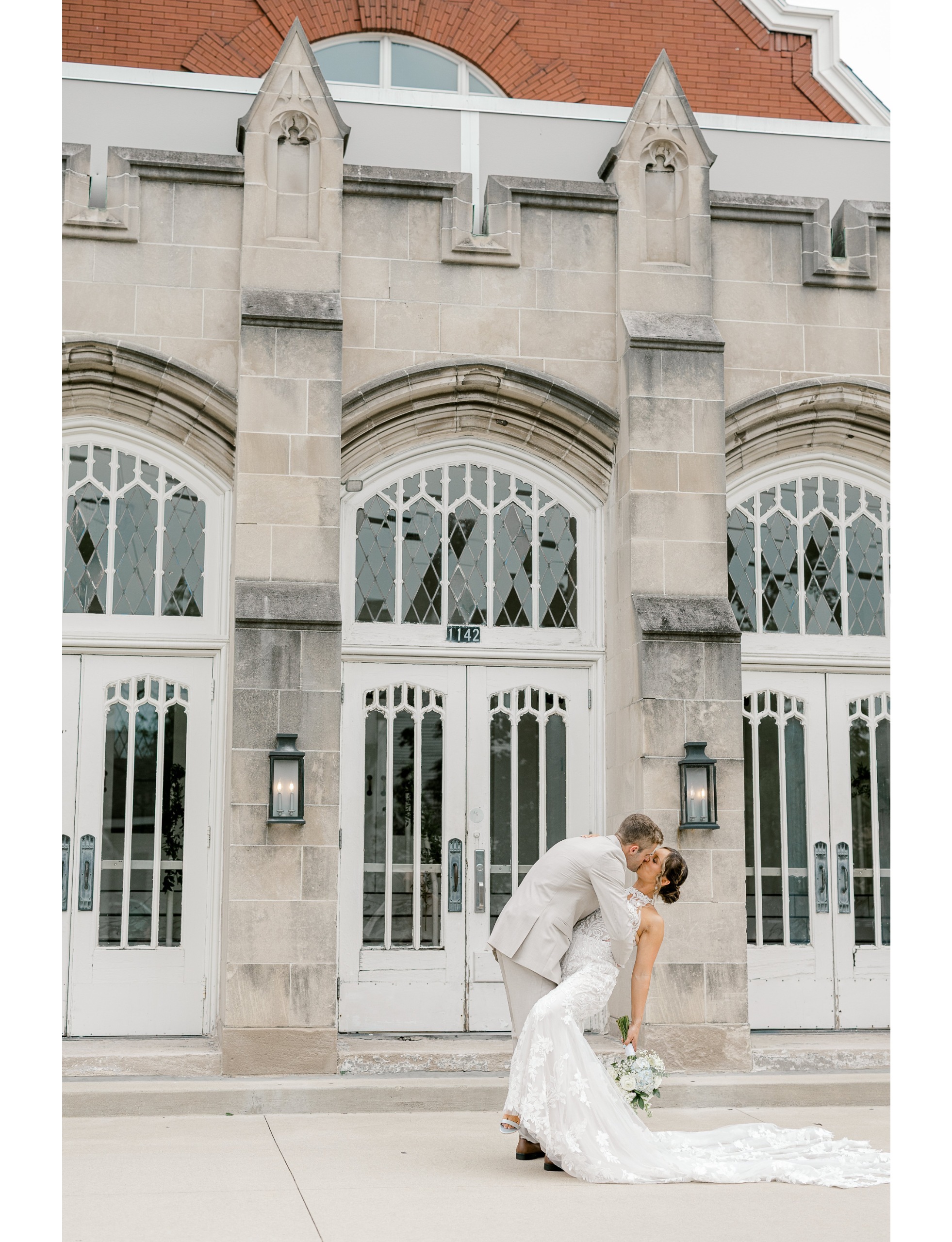 Groom dipping the bride for a kiss in front of the historic stone entrance of The Broadway Avenue in Grand Rapids