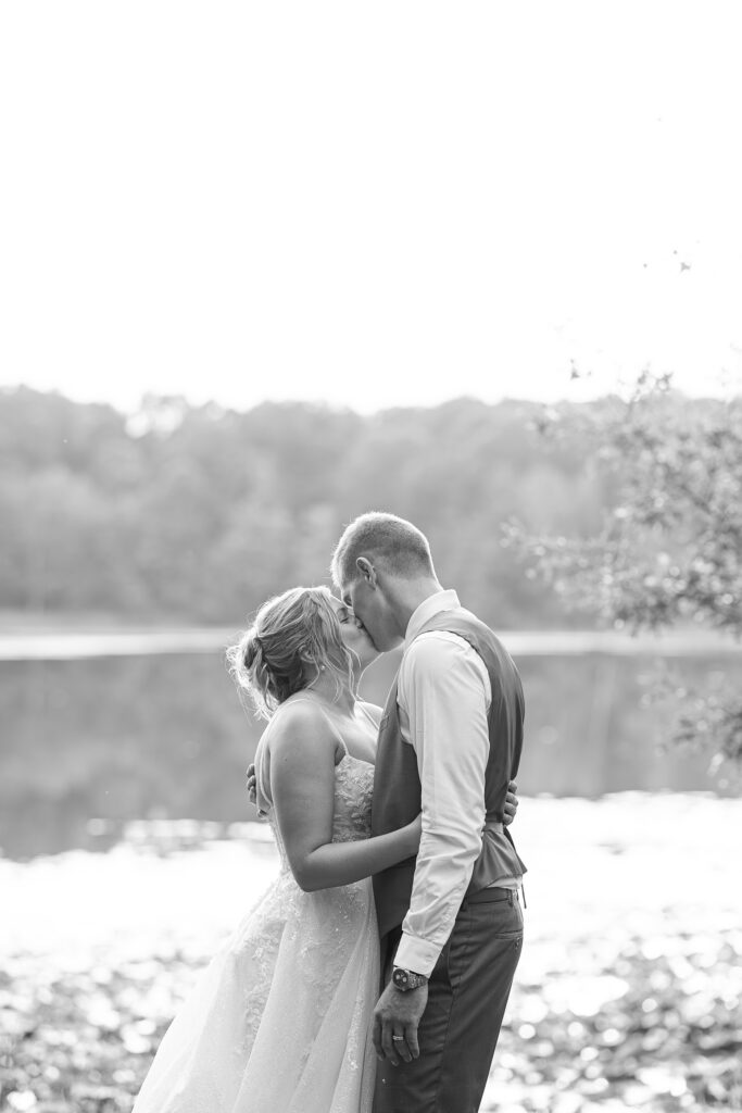 Black and white photo of the couple kissing by the lake