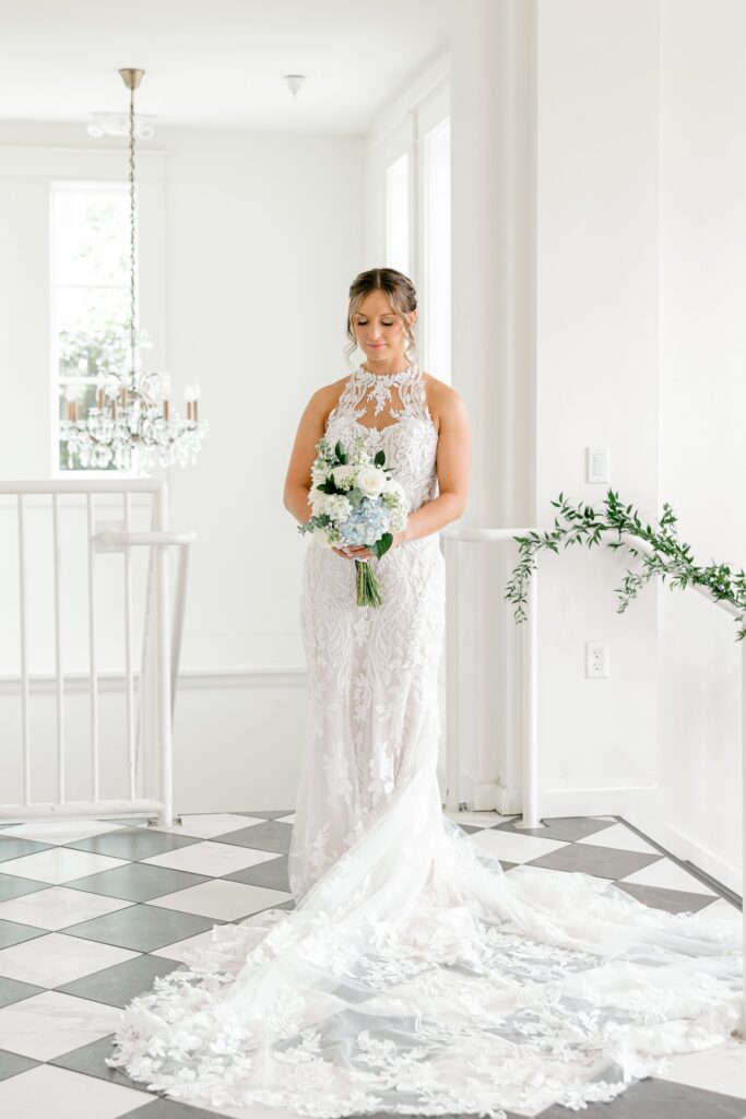Bride in her lace gown with a long train inside the white venue
