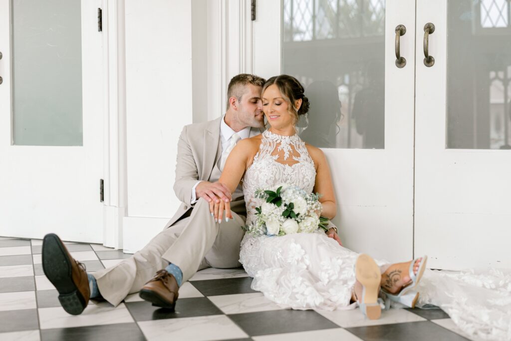Bride and groom sitting together on the black and white checkered floor at The Broadway Avenue