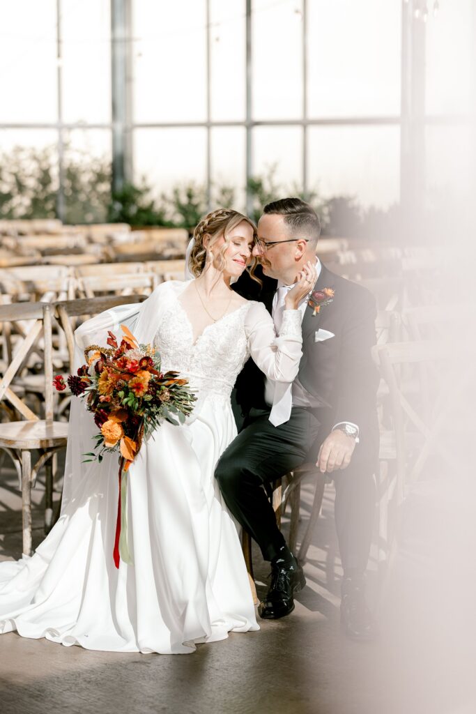 Bride and groom sitting close together inside the Ivy House greenhouse