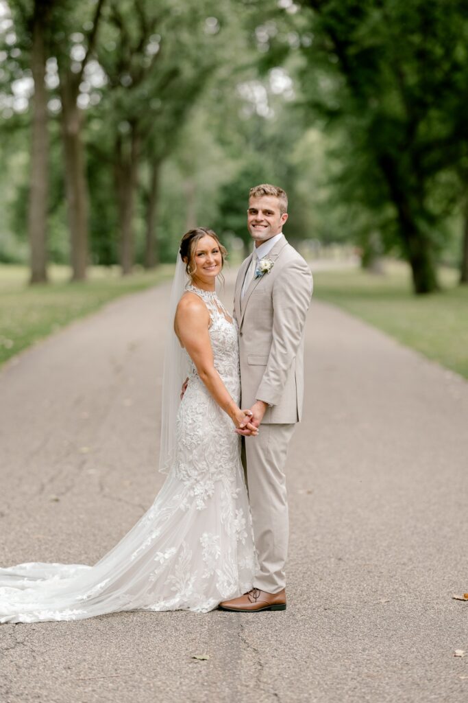 Bride and groom embracing on a tree-lined path on their wedding day