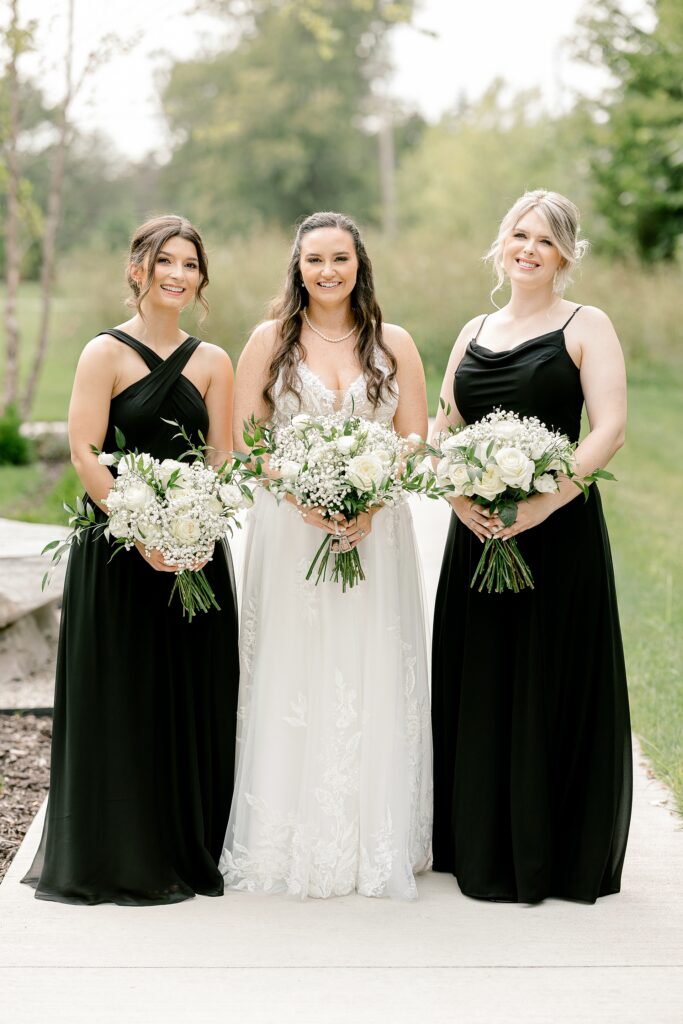 Bride with her bridesmaids in black dresses holding white bouquets