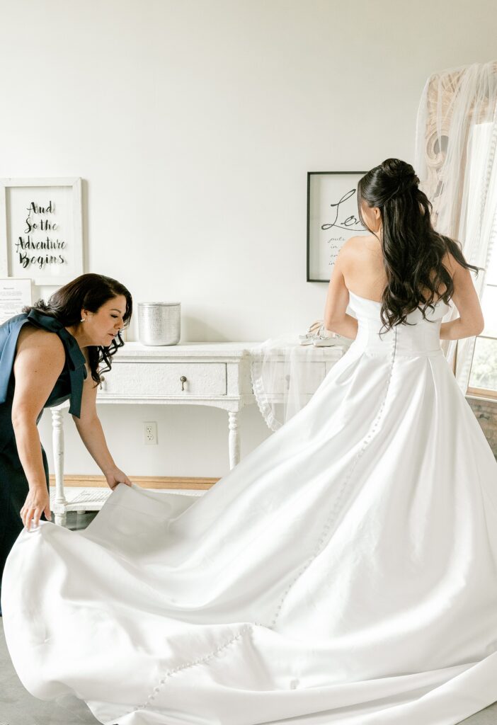 Bride getting into her ball gown with help on her wedding morning