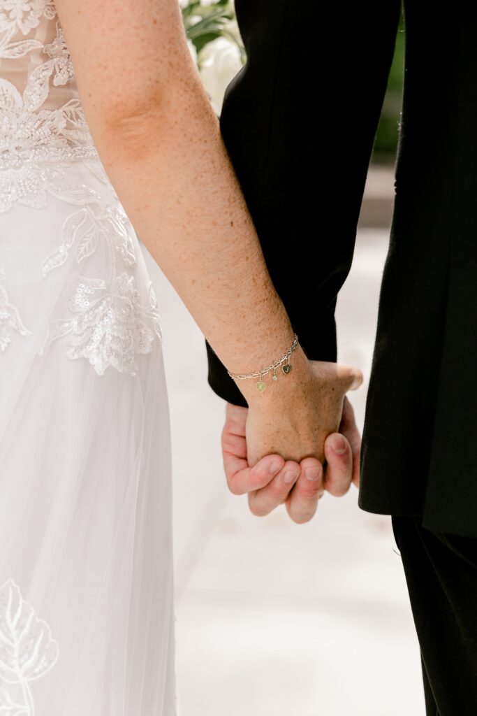 Close-up of the bride and groom holding hands