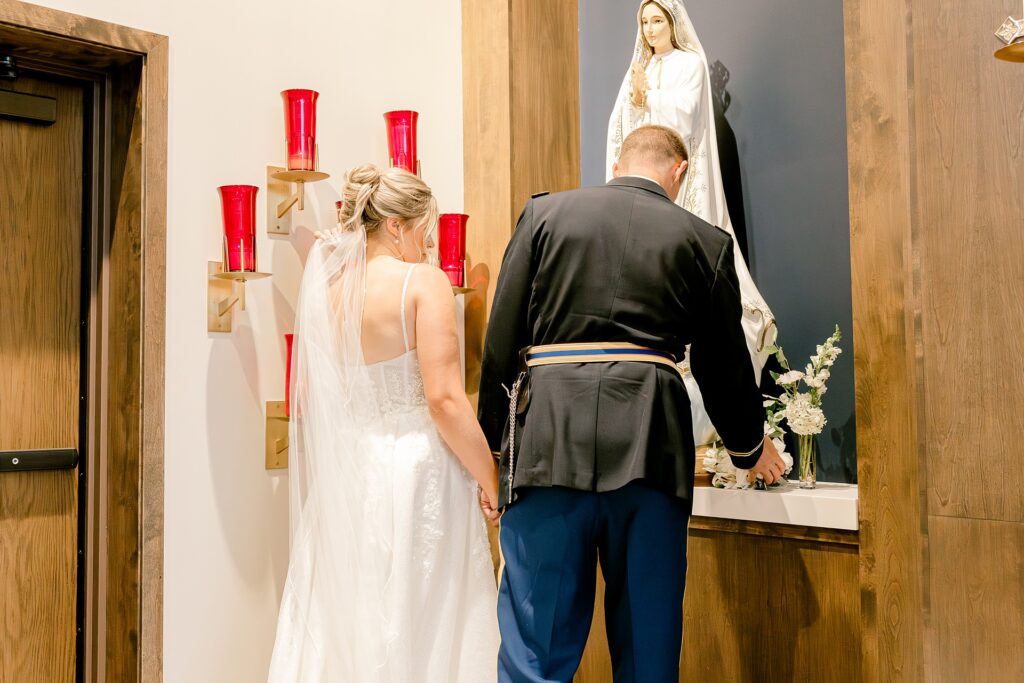 Bride and groom praying at the Marian statue during the ceremony