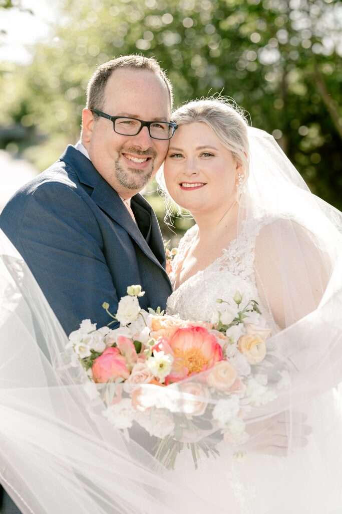 Bride and groom smiling cheek to cheek with her bouquet