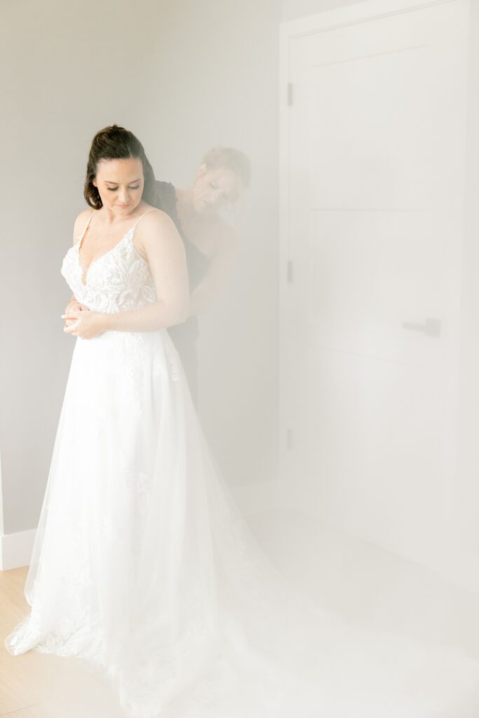 Bride in her lace gown by a window on her wedding morning