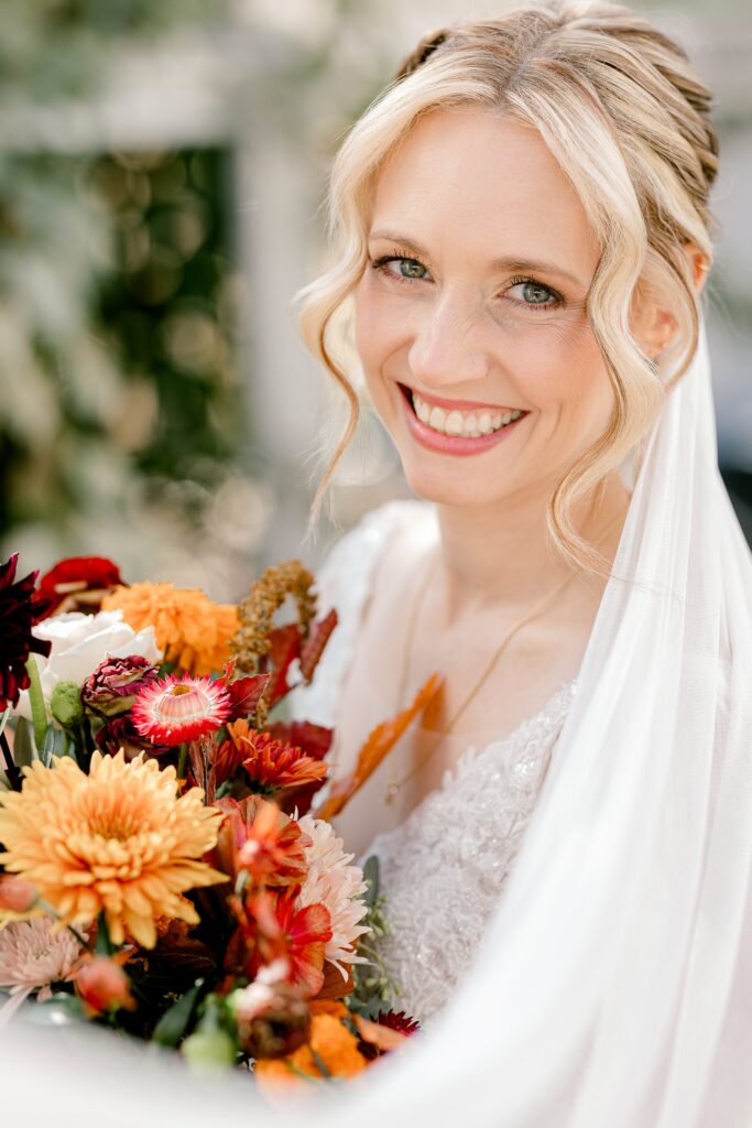 Close portrait of the bride smiling with a fall dahlia bouquet