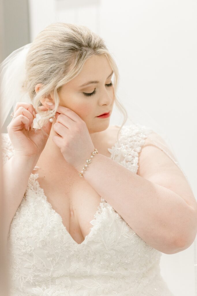 Bride putting on her earrings while getting ready