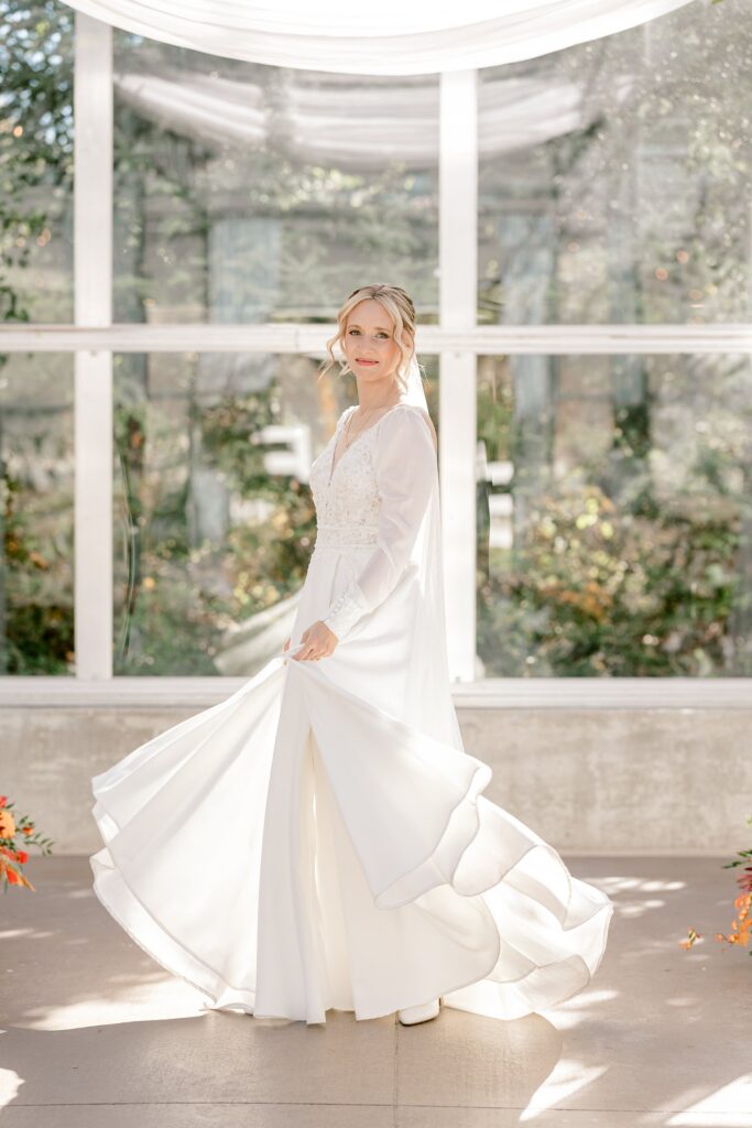 Bride twirling her wedding dress in the greenhouse at Ivy House
