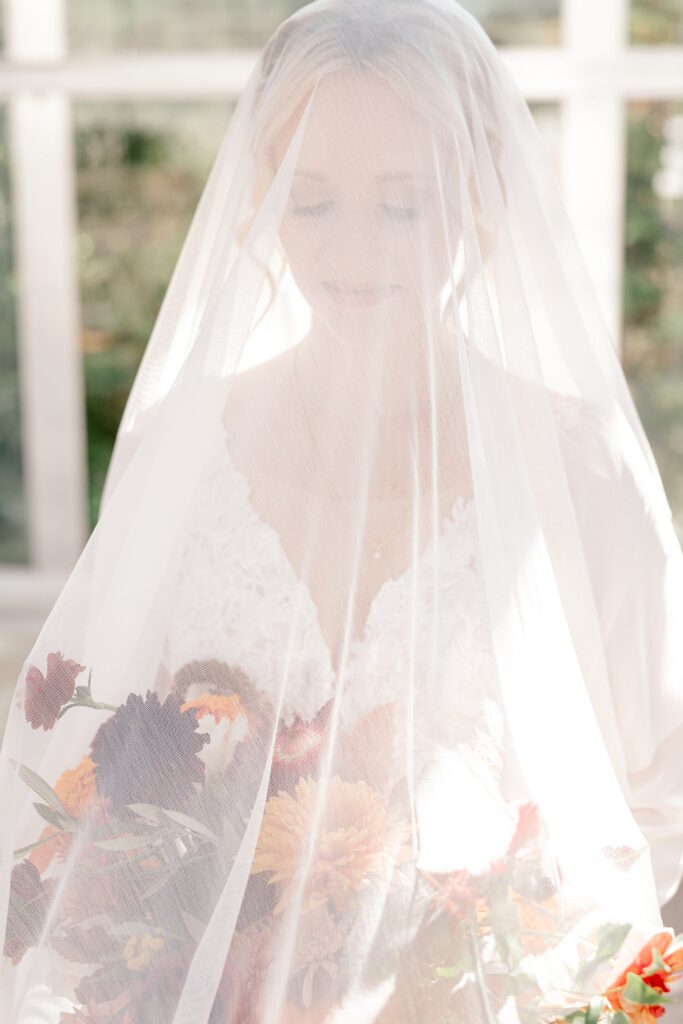 Editorial portrait of the bride under her veil with fall florals
