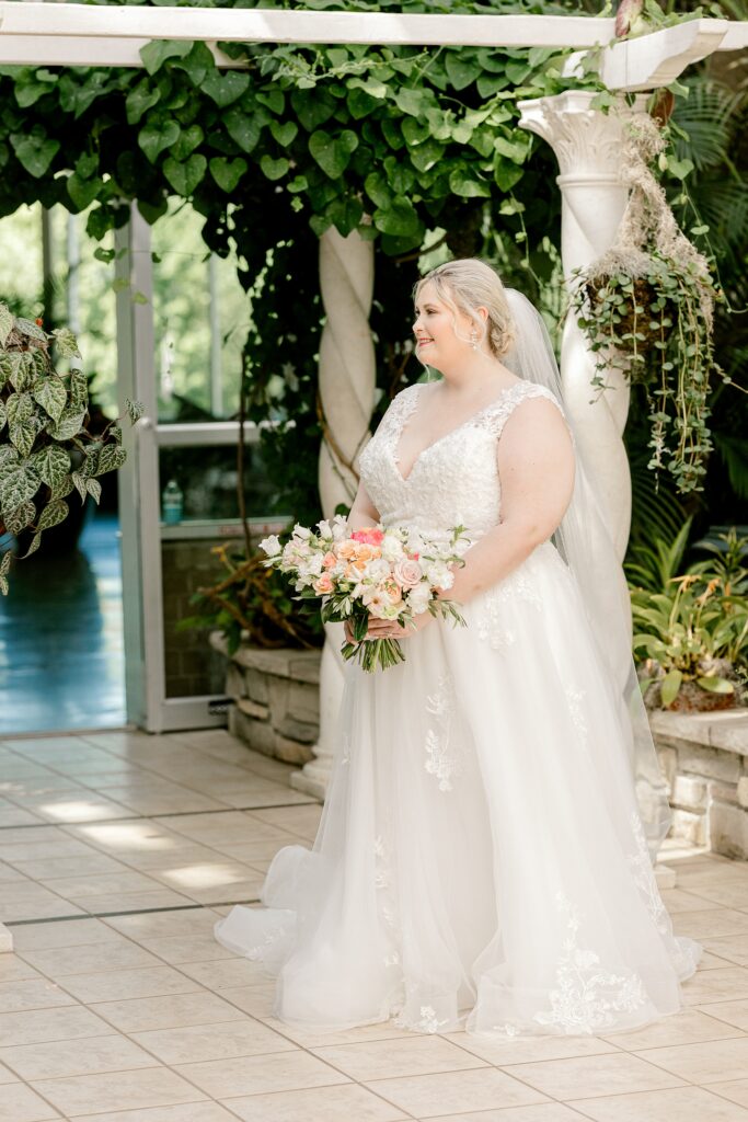 Bride walking toward her groom for their first look in the conservatory