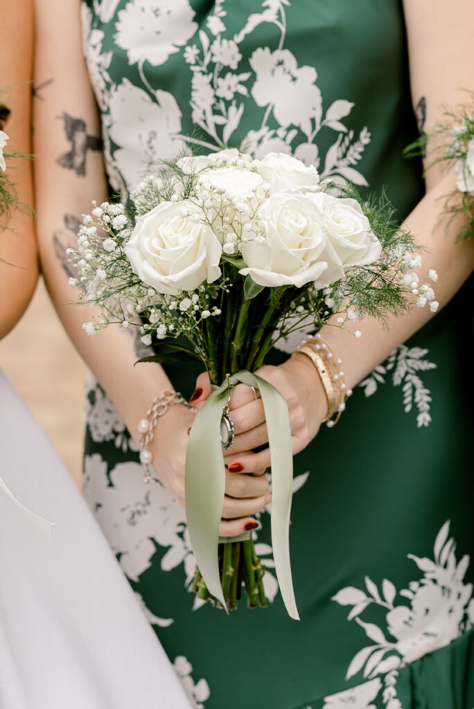 Bridesmaid in a green floral dress holding a white rose bouquet