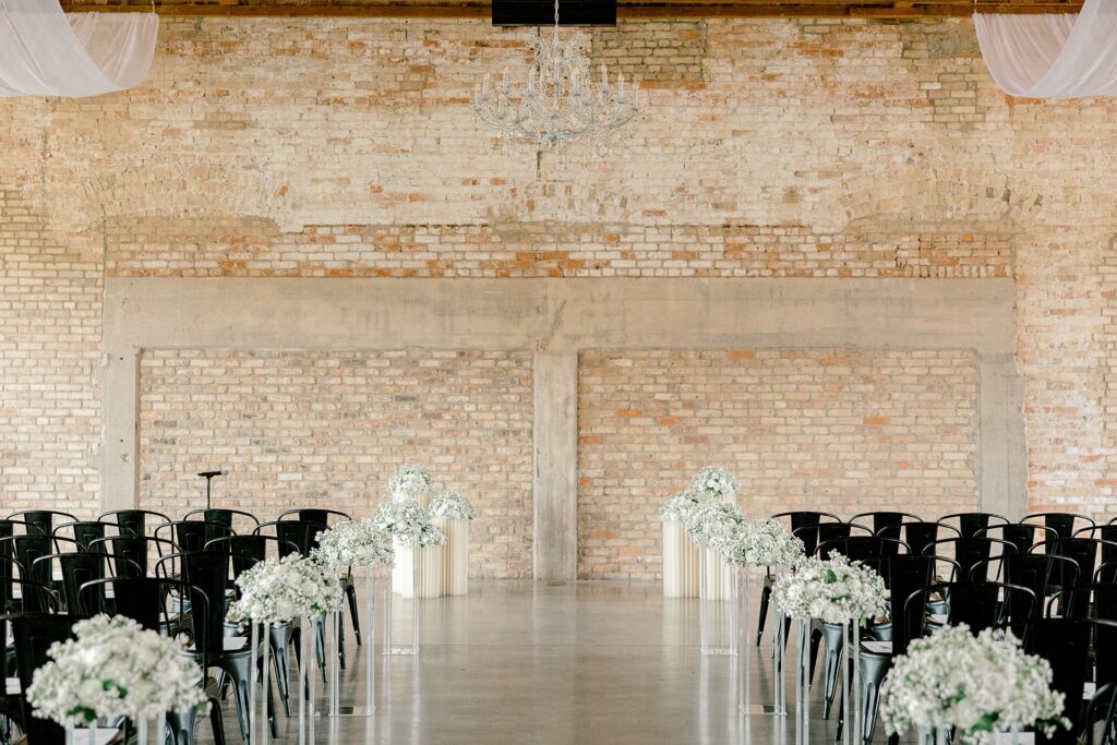 Ceremony space at The BRIX on Fox with black chairs and white aisle florals