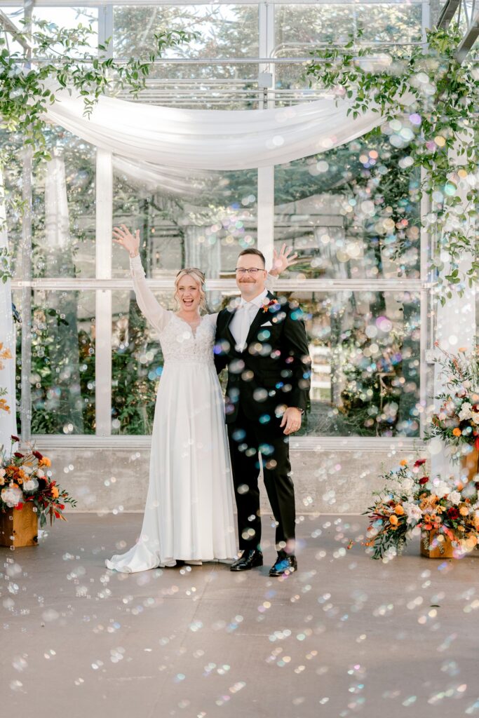 Bride and groom celebrating in a cloud of bubbles after the ceremony