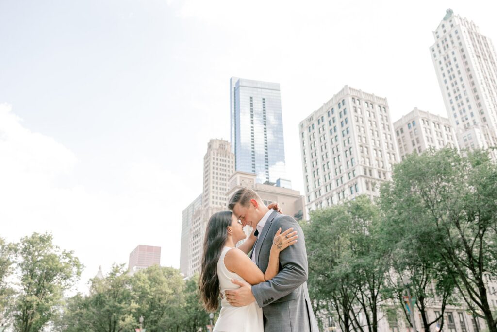 Engaged couple walking through a downtown Chicago park with the city skyline behind them