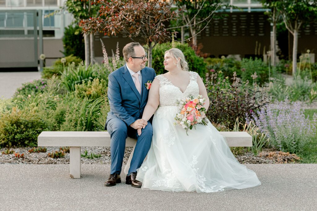 Bride and groom sitting on a garden bench at Frederik Meijer Gardens