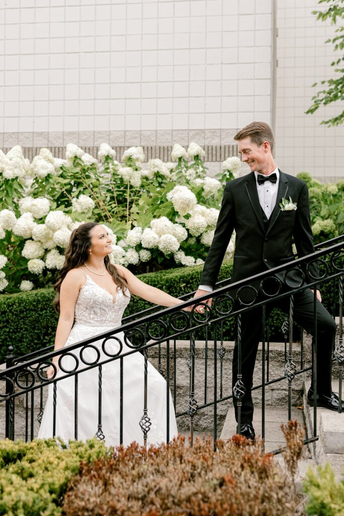 Bride and groom on the garden stairs surrounded by white hydrangeas