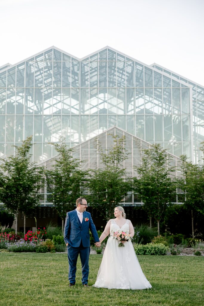 Bride and groom holding hands in front of the glass conservatory