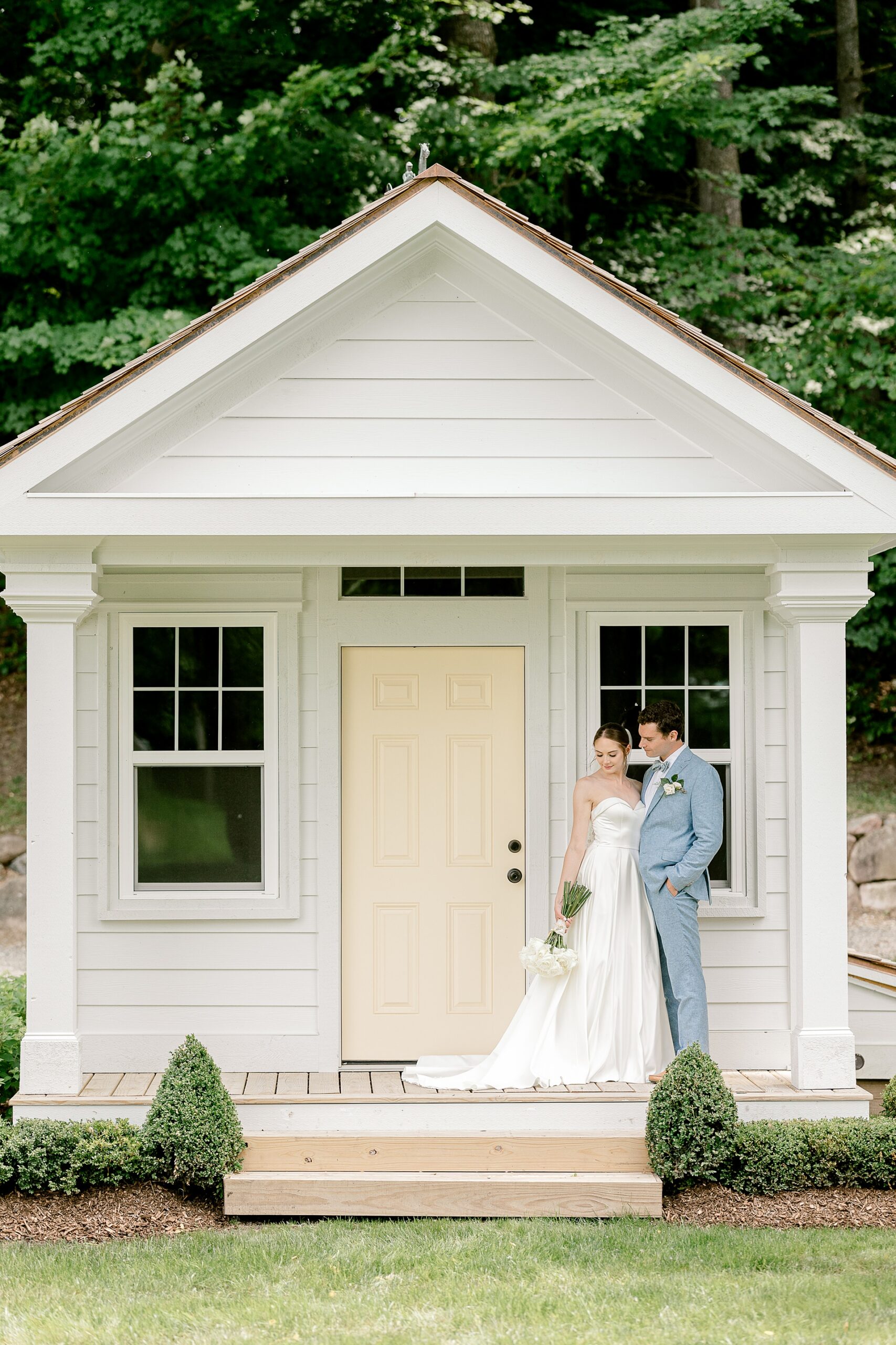 Bride and groom kissing in front of the white cottage