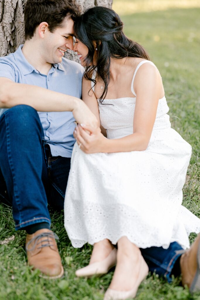 Couple snuggled together sitting in the grass at Riverside Park in Grand Rapids
