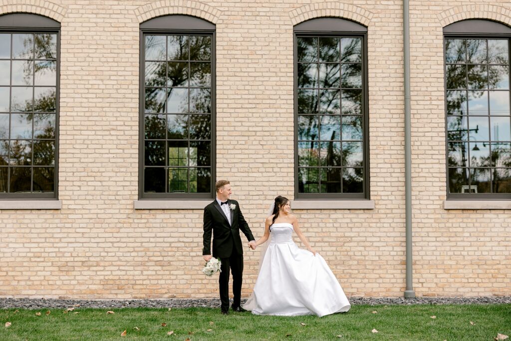 Bride and groom walking along the brick building at The BRIX on Fox