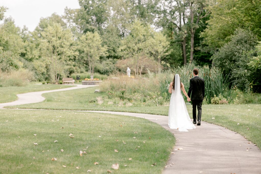 Bride and groom walking along a winding path through the grass