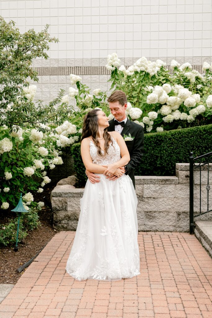Bride and groom in front of white hydrangeas