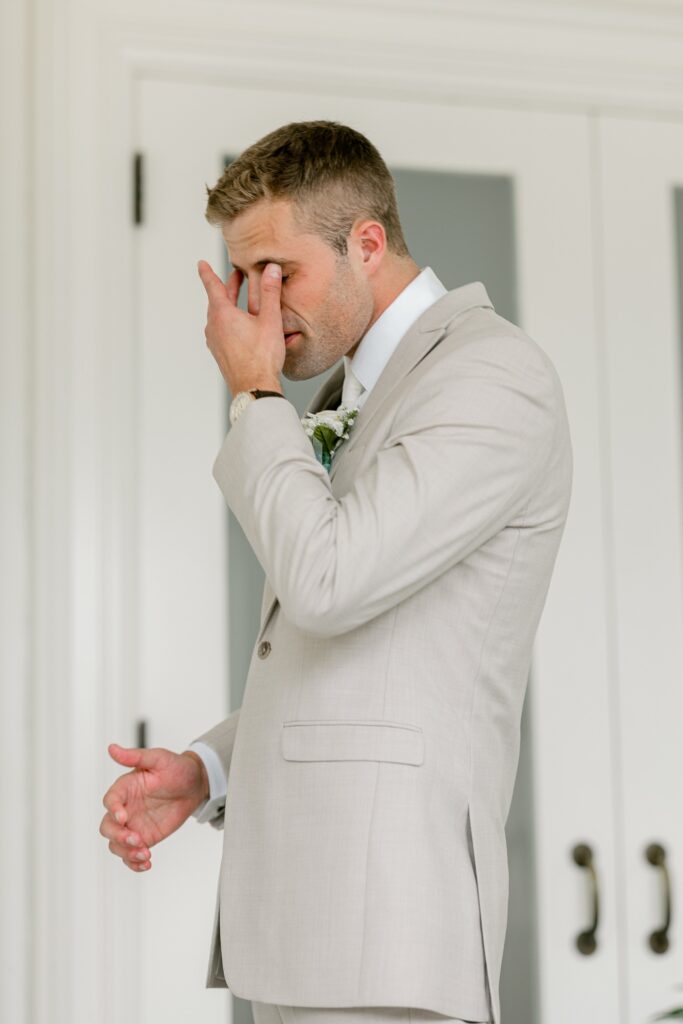 Emotional groom wiping a tear during the first look