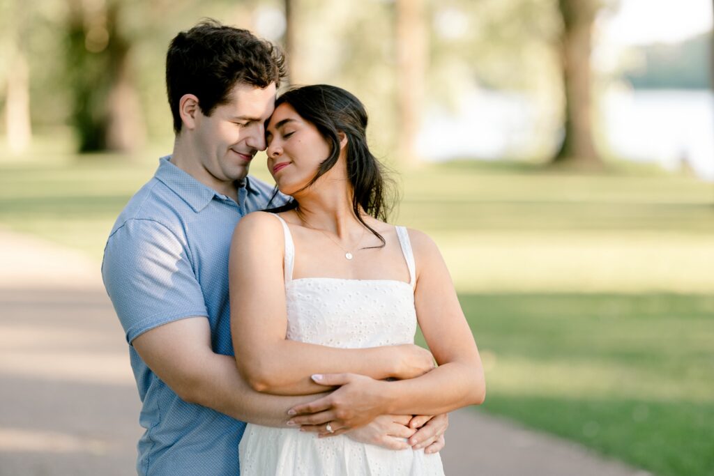 Engaged couple nuzzling close in the soft evening light at Riverside Park in Grand Rapids