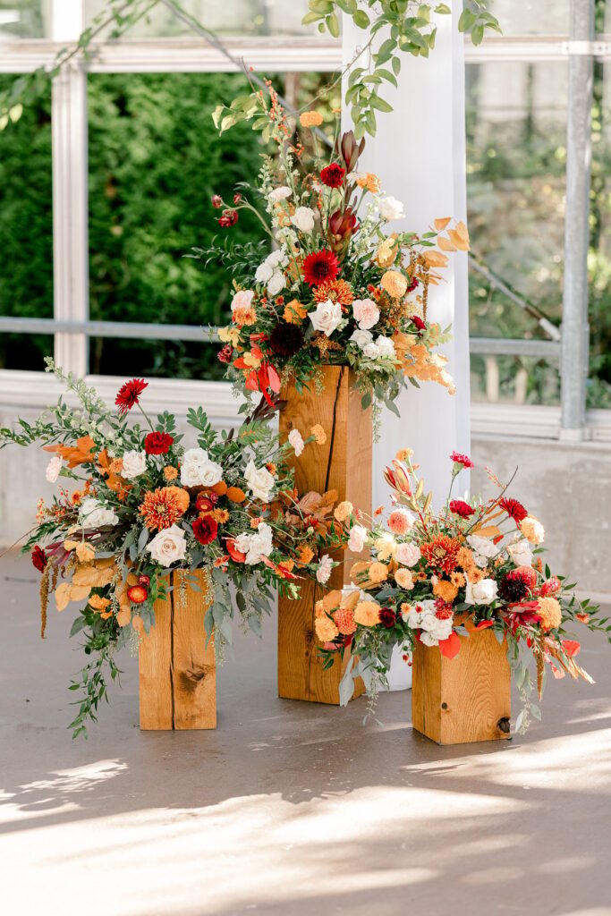 Fall floral arrangements on wooden pedestals inside the greenhouse