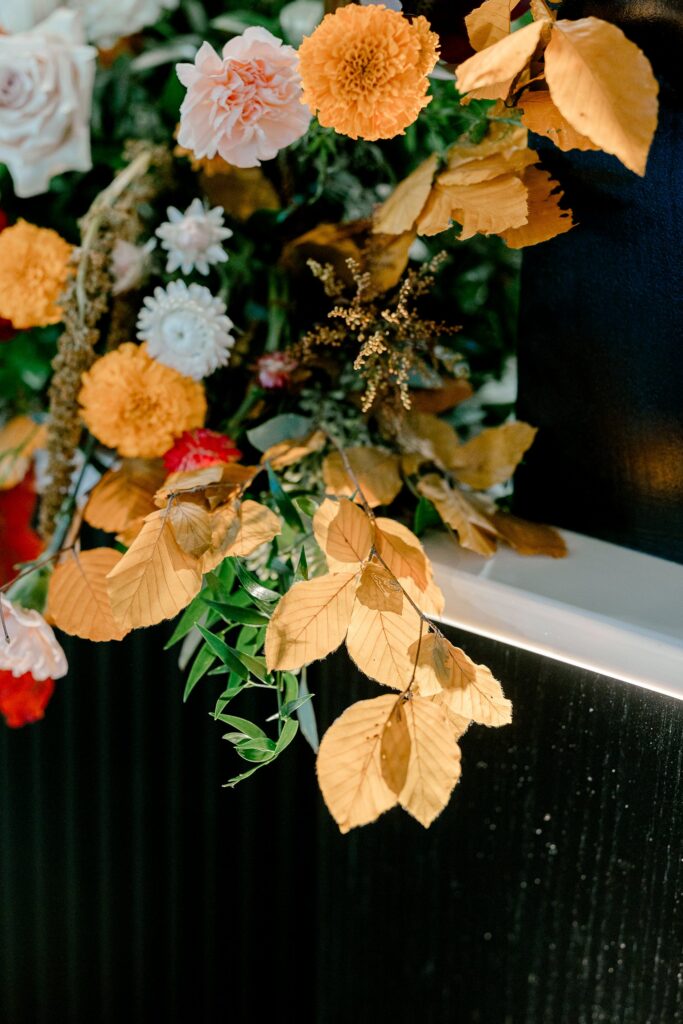 Reception florals with mustard and peach blooms and golden fall leaves