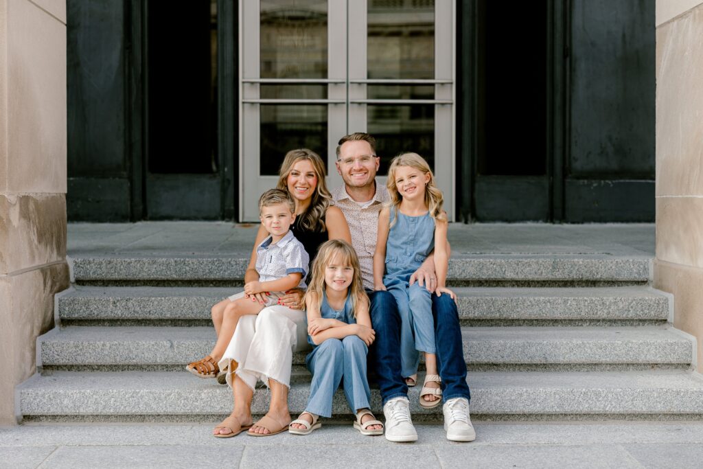 Family sitting together on the stone steps in front of the historic Civic Auditorium doors in downtown Grand Rapids