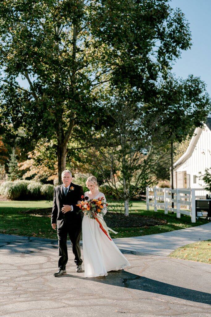 Bride's father walking her across the grounds to the greenhouse ceremony