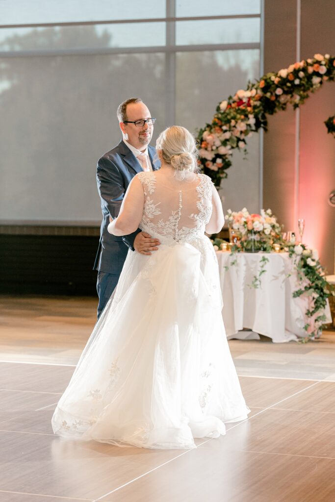 Bride and groom dancing in front of the floral arch