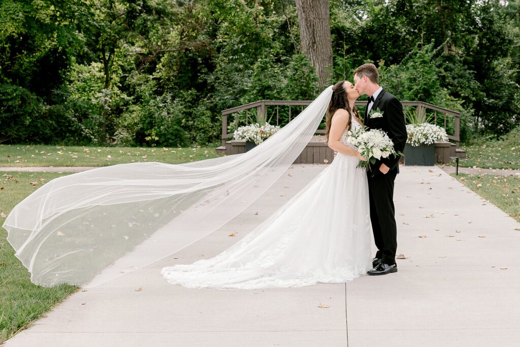 Bride and groom kissing after their first look on the church grounds with a long veil