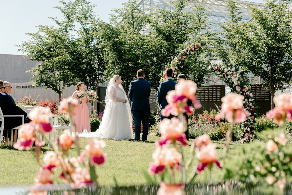 Bride and groom at the altar seen through garden flowers