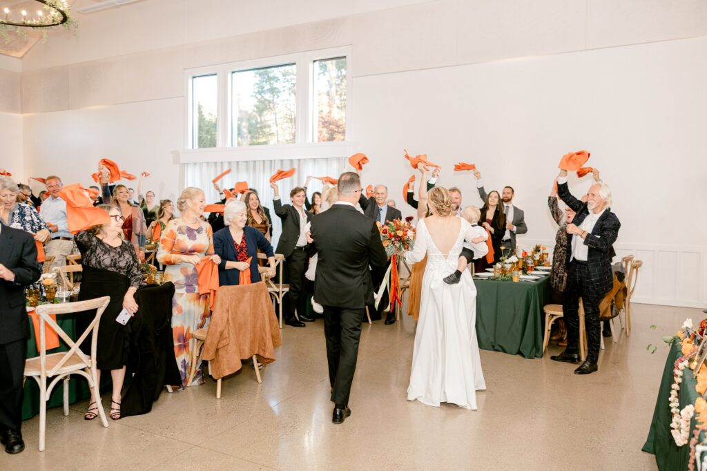 Bride and groom entering the reception as guests spin napkins over their heads