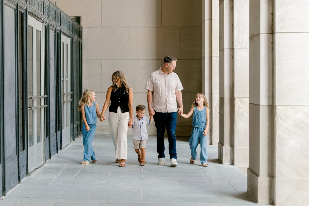 Family of five walking hand in hand through the stone colonnade of the Civic Auditorium in downtown Grand Rapids