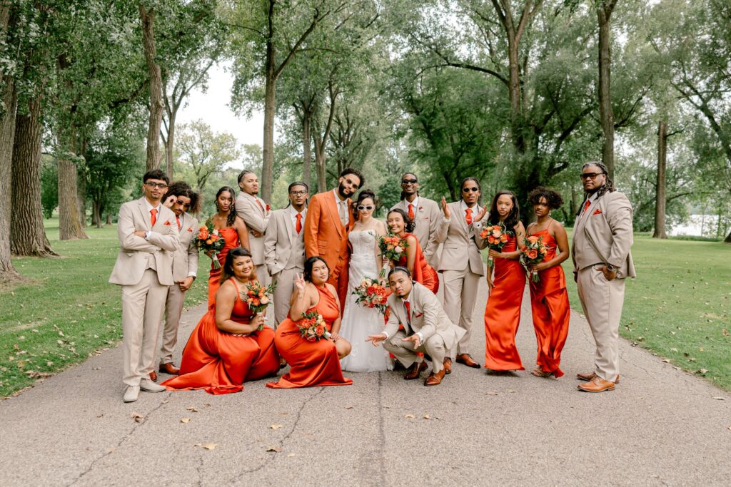 Wedding party in burnt orange dresses and tan suits at Riverside Park in Grand Rapids