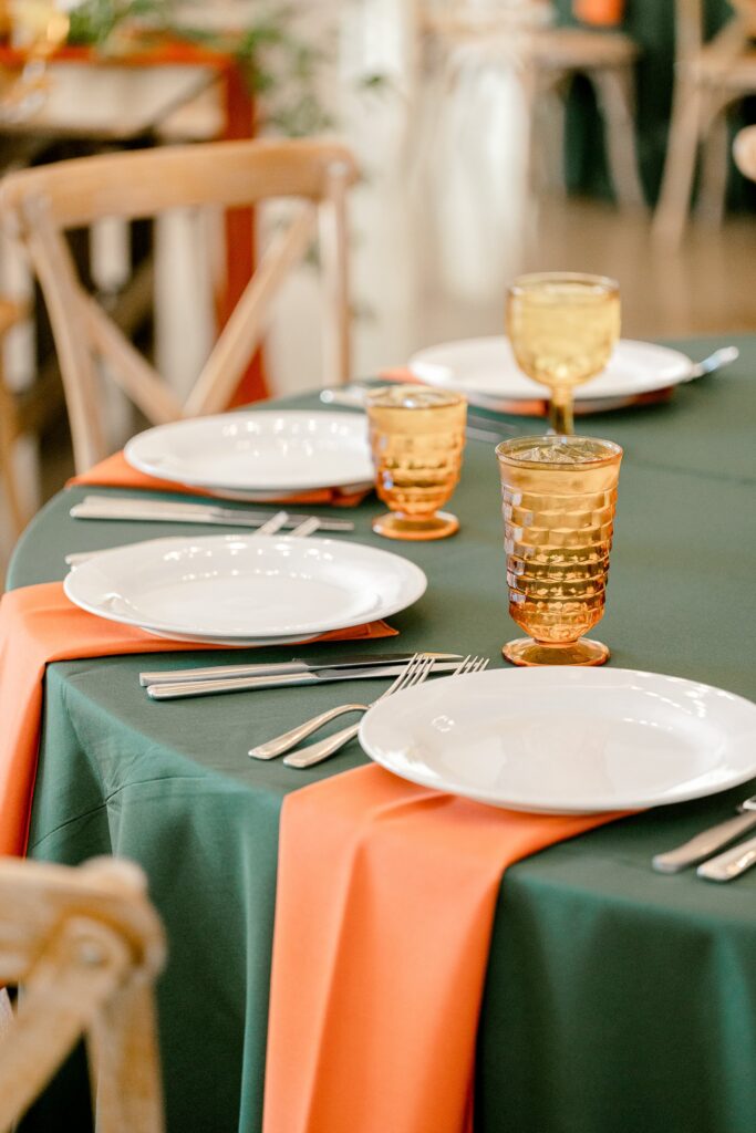 Table settings with green linens, rust napkins and amber glassware