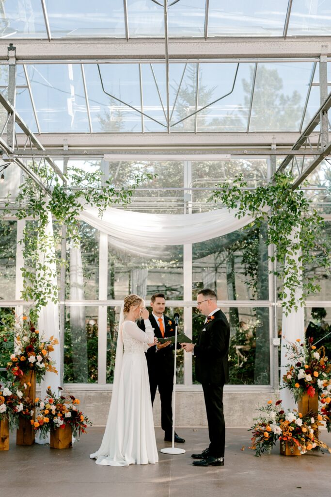 Bride and groom at the altar under the glass greenhouse roof